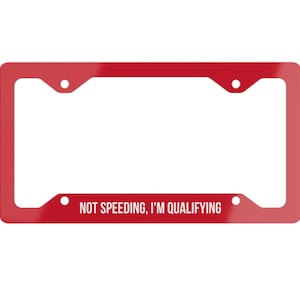 Op de afbeelding: Een rode kentekenplaathouder met de witte tekst "NOT SPEEDING, I'M QUALIFYING". De houder heeft vier montagegaten en een glanzende afwerking. Een leuk accessoire voor elk voertuig.