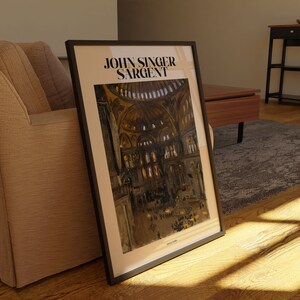 May include: Framed art print featuring a painting of a cathedral interior by John Singer Sargent. The artwork is in a black frame and has a beige border. The print displays a detailed depiction of the cathedral's architecture, with figures and warm tones.