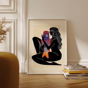 Pode incluir: Uma ilustração em preto e branco de uma mulher segurando um peixe colorido. A mulher está sentada com as pernas cruzadas e os braços envoltos em torno do peixe. O peixe tem um padrão vermelho, laranja, azul e branco.