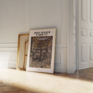 May include: A framed art print featuring a John Singer Sargent painting of a cathedral interior. The print has a gold frame and is leaning against a white wall. The text "JOHN SINGER SARGENT" is printed at the top of the artwork.