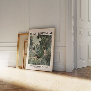 May include: A framed poster of a painting by Henri Rousseau titled "The Equatorial Jungle." The painting depicts a lush jungle scene with vibrant green foliage, pink flowers, and a monkey in the center.
