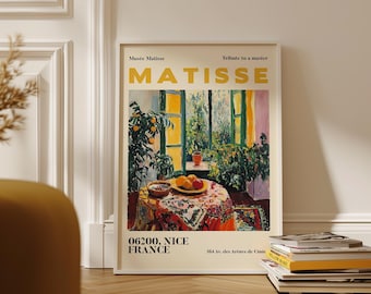 May include: A framed art print featuring a colorful interior scene with a table set with fruit and a patterned tablecloth. The print includes the text "Musée Matisse" and "MATISSE" in yellow, along with the location "06200, NICE FRANCE".