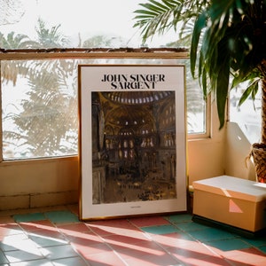 May include: A framed art print featuring the text "JOHN SINGER SARGENT" at the top. The artwork depicts a detailed interior scene with figures, likely a church or cathedral. The frame is gold-colored.