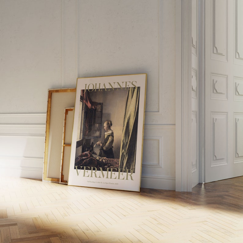 Pode incluir: Uma impress&atilde;o de arte emoldurada com a pintura de Johannes Vermeer, com o nome do artista no topo e o t&iacute;tulo da pintura abaixo. A impress&atilde;o est&aacute; encostada a uma parede, ao lado de uma tela em branco. A sala tem ch&atilde;o de parquet e paredes brancas.