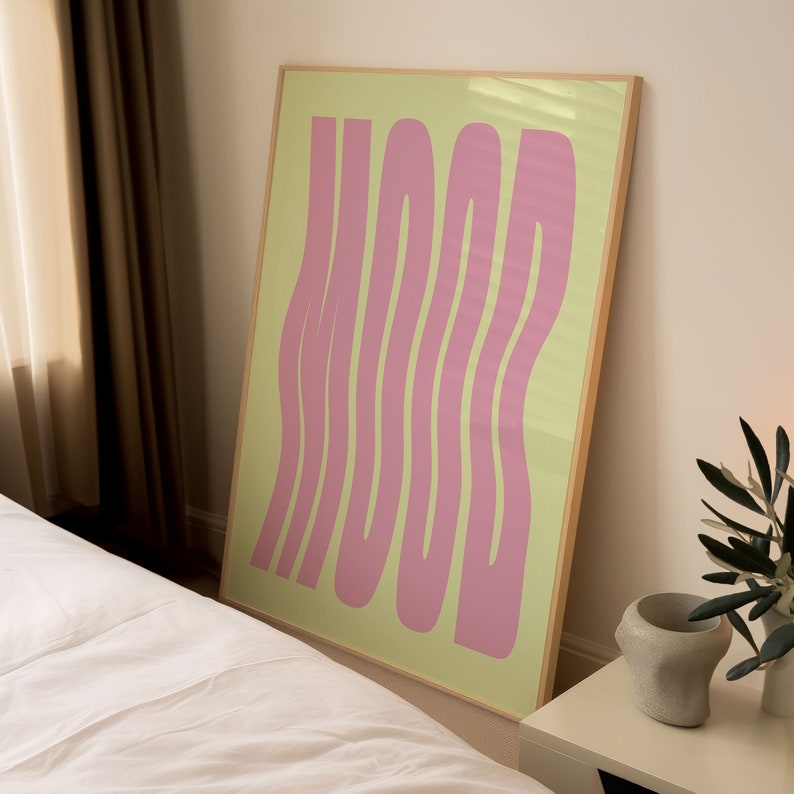 May include: A framed print with the word "MOOD" written in a pink, wavy font on a light green background.