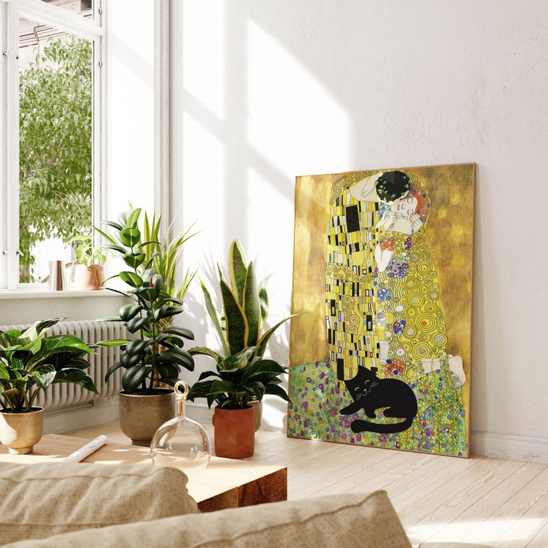 May include: A framed canvas print of Gustav Klimt's "The Kiss" with a black cat illustration at the bottom. The artwork features gold, yellow, and colorful floral patterns. The print is displayed in a well-lit room with potted plants.