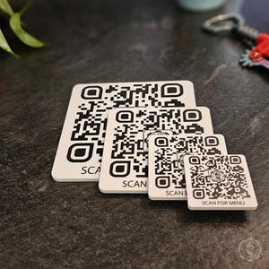 May include: Four white square coasters with black QR codes and the text "SCAN FOR MENU" on the smallest coaster.