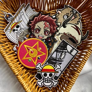 Könnte beinhalten: Eine Sammlung bunter gestickter Anime-Charakter-Patches, darunter ein roter und weißer Stern, ein weißer Schädel mit einem roten und gelben Hut, ein weißer und schwarzer Charakter mit einem Schwert, ein weißer und brauner Charakter mit einem roten Auge und ein weißer und schwarzer Charakter mit einem roten Auge.
