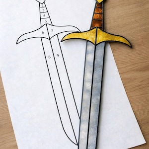 Może przedstawiać: Miecz witrażowy ze srebrnym ostrzem, złotym jelcem i brązową rękojeścią. Rysunek linii miecza znajduje się na białej kartce papieru. Miecz ma dekoracyjny design i prawdopodobnie jest dekoracją ścienną.