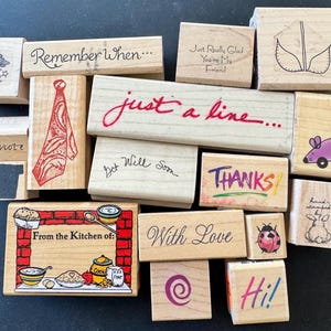 May include: A collection of rectangular wooden rubber stamps featuring various designs including a tie, a mouse, a ladybug, a kitchen scene with the text From the Kitchen of, and phrases like Remember When, just a line, and With Love.