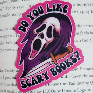 May include: A pink and purple sticker with a cartoon ghost holding a knife. The sticker says "Do You Like Scary Books?"