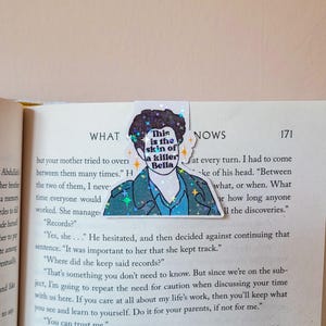 Op de afbeelding: Een holografische sticker met een cartoonillustratie van een persoon met de tekst "This is the skin of a killer Bella" op een witte achtergrond.