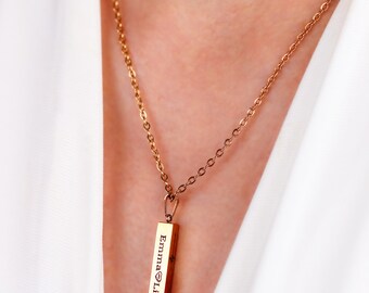 May include: A gold necklace with a bar pendant engraved with the names "Emma" and "Liam" separated by a heart symbol.