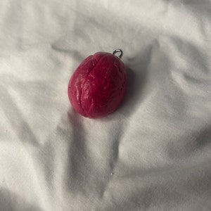 May include: A small, red, brain-shaped charm with a silver loop for hanging.