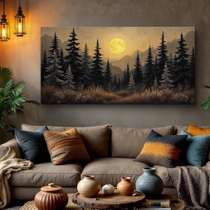 May include: A canvas print of a forest scene with a full moon in the sky. The forest is made up of tall, dark green trees. The moon is a bright yellow color. The print is hanging on a wall in a living room with a brown couch and pillows.
