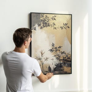 Pu&ograve; includere: Una stampa d'arte astratta incorniciata con uno sfondo dorato e piante stilizzate in nero e grigio. La stampa &egrave; appesa a una parete bianca.