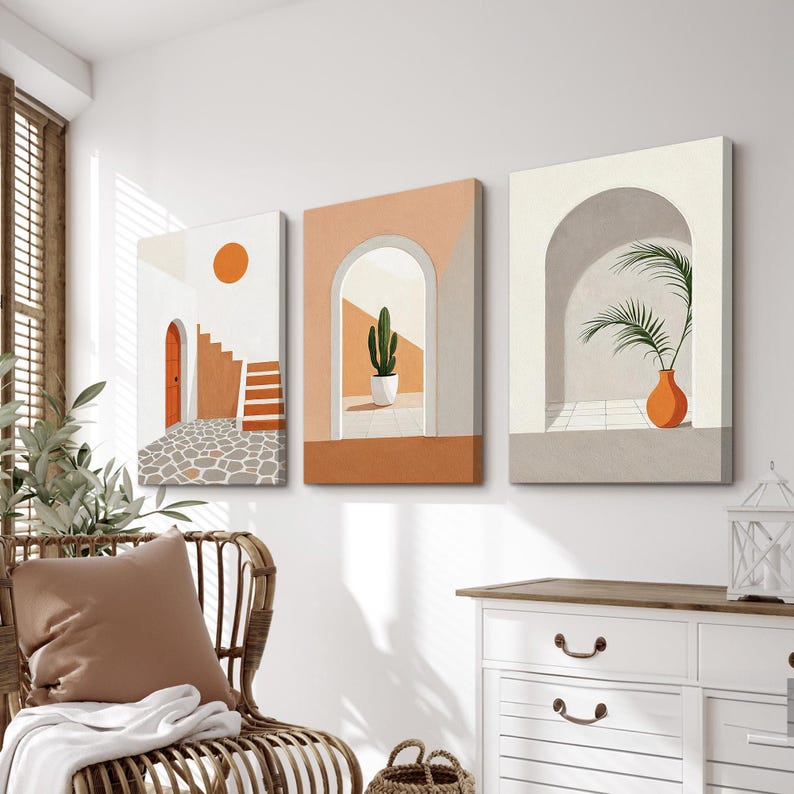 May include: A set of three rectangular canvas wall art prints featuring architectural scenes. The first shows a stone patio with an orange door and sun, the second an arched doorway with a potted cactus, and the third an arched alcove with a palm plant.