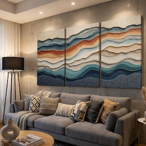 May include: A triptych wall art set featuring layered, wavy horizontal bands in shades of deep blue, teal, cream, and burnt orange. The textured panels create a topographical effect, mounted side-by-side to form a continuous abstract landscape.