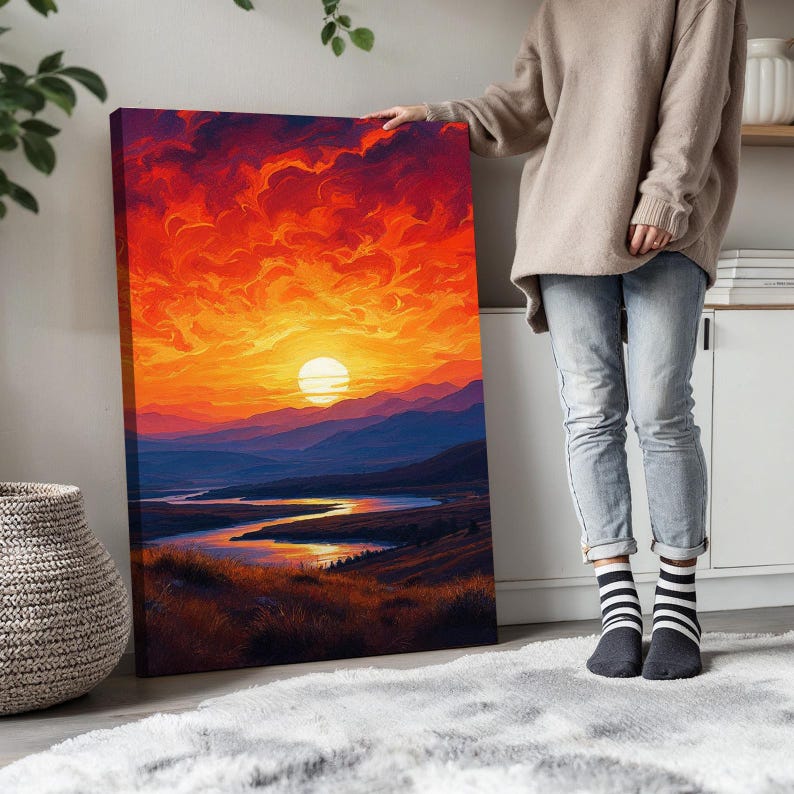 K&ouml;nnte beinhalten: Ein Leinwanddruck einer Landschaftsszene mit einem feurigen orangen Sonnenuntergang &uuml;ber einem Fluss und Bergen. Die Sonne ist ein leuchtend gelber Kreis am Himmel.