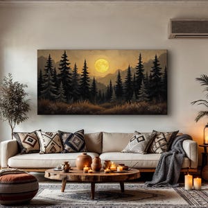 May include: A canvas print of a forest scene with a large, yellow moon in the sky. The print is hanging on a wall in a living room with a couch, pillows, and a coffee table.