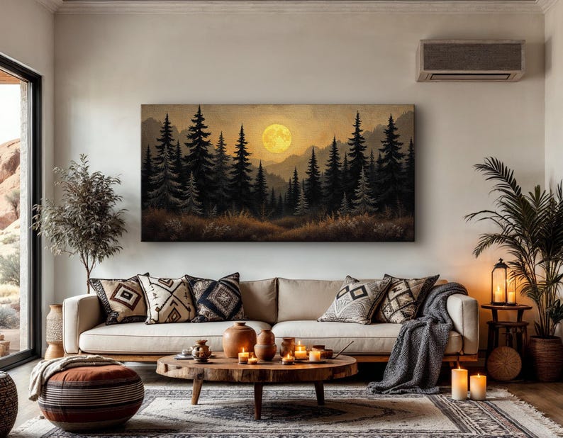 May include: A canvas print of a forest scene with a large, yellow moon in the sky. The print is hanging on a wall in a living room with a couch, pillows, and a coffee table.