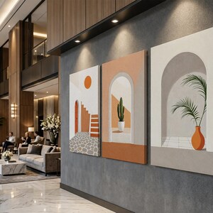 May include: A set of three rectangular canvas wall art prints featuring architectural scenes. The designs include a stone courtyard with stairs and a sun, a cactus in an arched doorway, and a potted palm plant inside a white arched alcove.