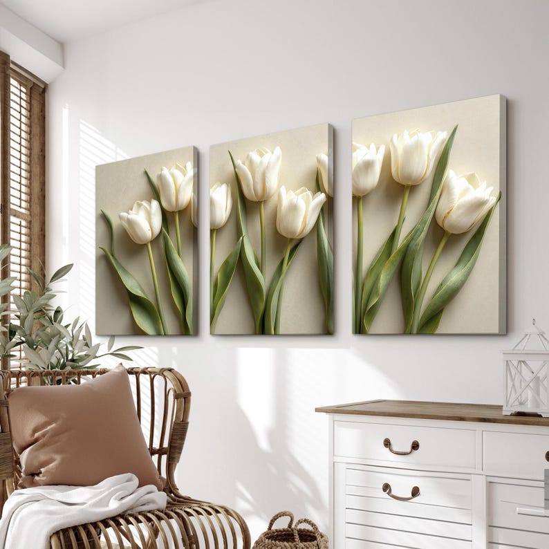 May include: Three-panel wall art featuring white tulip flowers with green stems and leaves against a neutral background. The artwork is displayed in a well-lit room with a wicker chair and a white dresser.