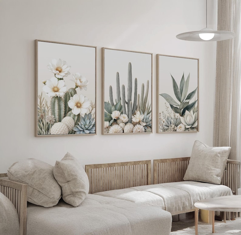 May include: Three framed botanical prints featuring watercolor illustrations of cacti and succulents. The artwork showcases a neutral color palette with beige, green, and white tones. The prints are displayed above a light-colored sectional sofa.