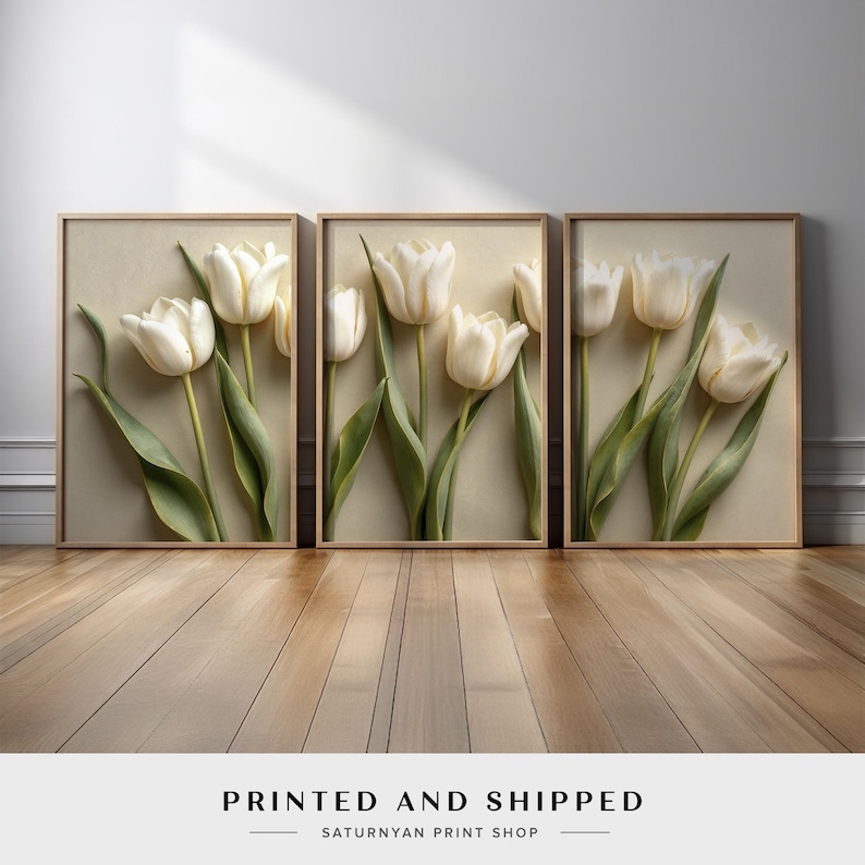 May include: Three framed art prints featuring white tulip flowers with green stems and leaves. The tulips are set against a neutral background, with a light wooden frame. The text "PRINTED AND SHIPPED" is at the bottom.