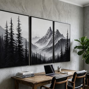 May include: A triptych wall art set featuring a black and white landscape of tall pine trees and jagged mountain peaks. The three rectangular canvases are framed in black and displayed side-by-side, depicting a misty forest and mountain range.