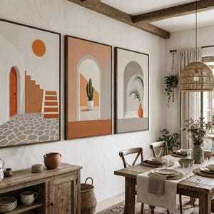 May include: A triptych of framed wall art prints featuring architectural scenes with arched doorways, a staircase, a cactus, and a potted plant in shades of orange, beige, and gray, displayed on a textured white wall above a wooden sideboard.