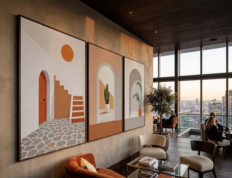 May include: A triptych of framed wall art featuring architectural scenes in warm earth tones. The panels display a white building with an orange door, a staircase, a cactus in a white pot within an archway, and a potted plant in a gray archway.