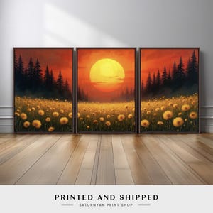 May include: Triptych art print featuring a sunset over a field of yellow flowers and dark trees. The sky is a gradient of orange and red. The artwork is framed in dark brown and displayed on a wooden floor.
