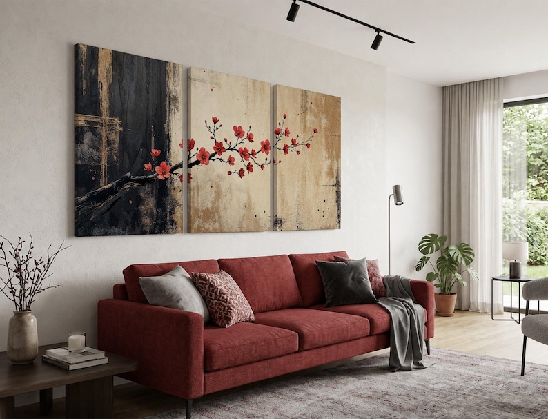 K&ouml;nnte beinhalten: Ein dreiteiliges Leinwand-Wandkunst-Set mit einem dunkel schwarzen und goldenen strukturierten Hintergrund auf der linken Seite, der in einen hellbeigen Hintergrund auf der rechten Seite &uuml;bergeht, mit einem Ast voller leuchtend roter Kirschbl&uuml;ten.