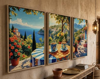 May include: A triptych of framed canvas wall art depicting a Mediterranean coastal scene. The paintings feature a terrace with potted orange flowers, a table with a checkered tablecloth, and two steaming mugs of coffee overlooking a blue sea.