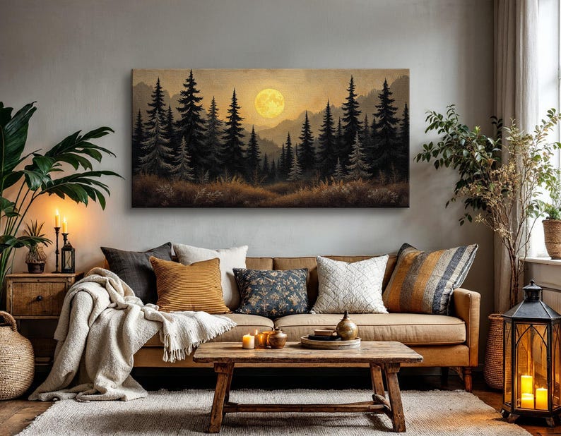 May include: A brown leather sofa with a throw blanket and pillows in front of a canvas print of a forest scene with a full moon. The print is framed and hanging on a gray wall.
