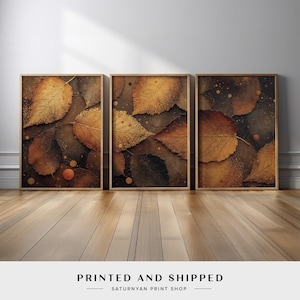 May include: Three framed prints of a close-up of autumn leaves with a textured, gold-like finish. The leaves are layered and overlapping, creating a sense of depth. The background is a dark brown with small, scattered gold dots.