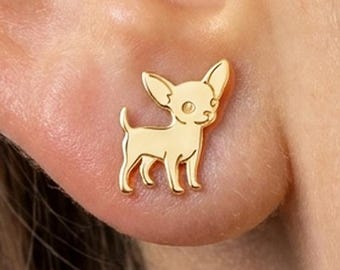 Puede incluir: Un pendiente de botón dorado con forma de perro pequeño, orejas puntiagudas y cola delgada. El pendiente presenta una superficie lisa y pulida, fijado directamente al lóbulo de la oreja, mostrando la silueta detallada de un chihuahua.