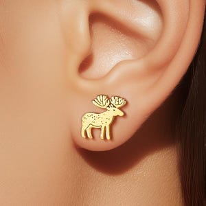 Puede incluir: Pendientes de botón dorados con forma de alce. Los pendientes presentan un diseño detallado de alce con cornamenta y cuerpo texturizado. Los pendientes son pequeños y delicados, adecuados para el uso diario.
