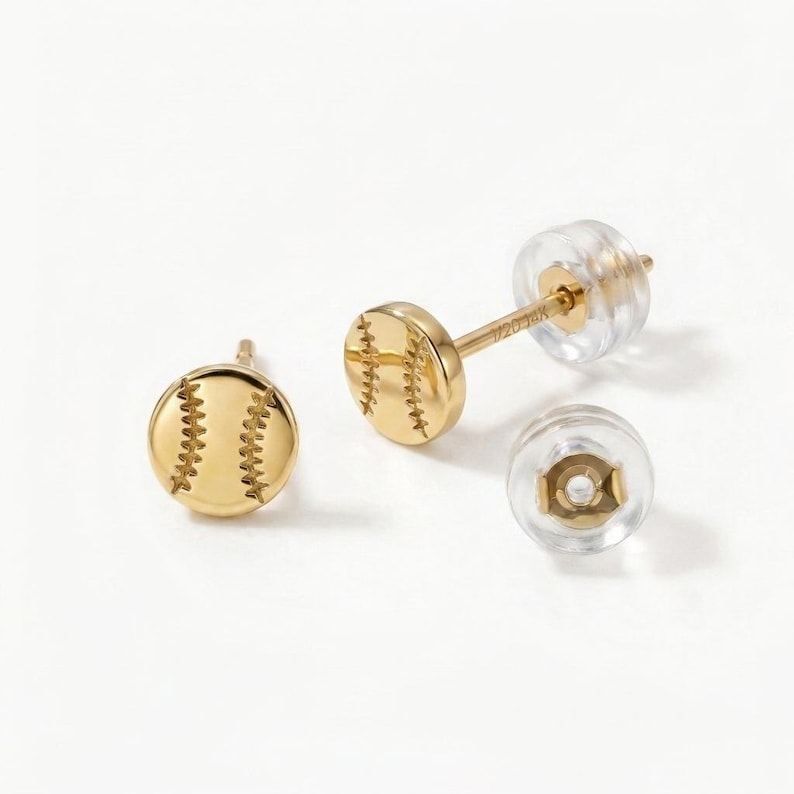 Pair of gold baseball stud earrings on white with clear silicone backs and 14k post stamp