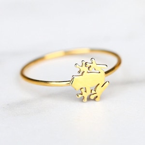 May include: A gold ring with a delicate frog design. The frog is sitting on a branch with leaves.
