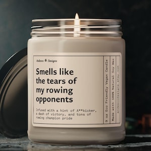 May include: A 9 ounce soy wax candle in a clear glass jar with a white label. The label reads "Smells like the tears of my rowing opponents" and "Infused with a hint of A**kicker, a dash of victory, and tons of rowing champion pride".
