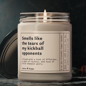 Peut inclure: Une bougie en cire de soja de 9 onces dans un pot en verre avec une étiquette blanche qui indique "Smells like the tears of my kickball opponents". L'étiquette comprend également le texte "Infused with a hint of A**kicker, a dash of victory, and tons of field champion glory." et "Andesco Designs".