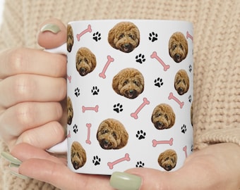 May include: White ceramic mug with a repeating pattern of a brown dog's face, pink bones, and black paw prints.