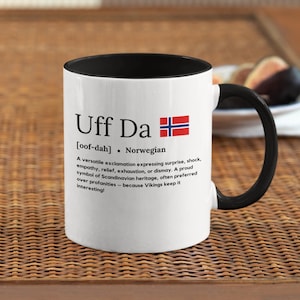 以下が含まれることがあります： 黒縁と持ち手のある白いセラミック製のコーヒーカップ。カップには、ノルウェーの国旗の白黒のイラストと「Uff Da [oof-dah] Norwegian」というテキストが描かれています。旗の下のテキストは、「Uff Da」というフレーズの、驚き、ショック、共感、安堵、疲労、落胆など、さまざまな感情を表す万能な感嘆符としての意味を説明しています。それはスカンジナビアの遺産の誇り高い象徴であり、バイキングがそれを面白く感じるため、しばしば冒涜よりも好まれます！