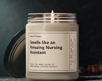 May include: A 9 ounce soy wax candle in a clear glass jar with a black lid. The candle is labeled "Smells like an Amazing Nursing Assistant" and "Enjoy the sweet aroma of 100% badass miracle worker!"