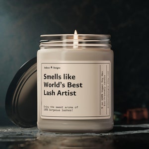 May include: A white candle with a black label that reads "Smells like World's Best Lash Artist" and "Enjoy the sweet aroma of 188 Gorgeous lashes!" The candle is in a glass jar with a black lid.