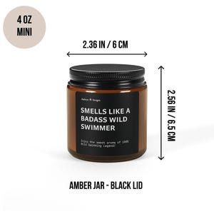 May include: A 4 ounce amber glass candle jar with a black lid. The candle is labeled "Smells Like a Badass Wild Swimmer" and has the text "Enjoy the sweet aroma of 100% Wild Swimming Legend!" The jar is 2.36 inches wide and 2.56 inches tall.