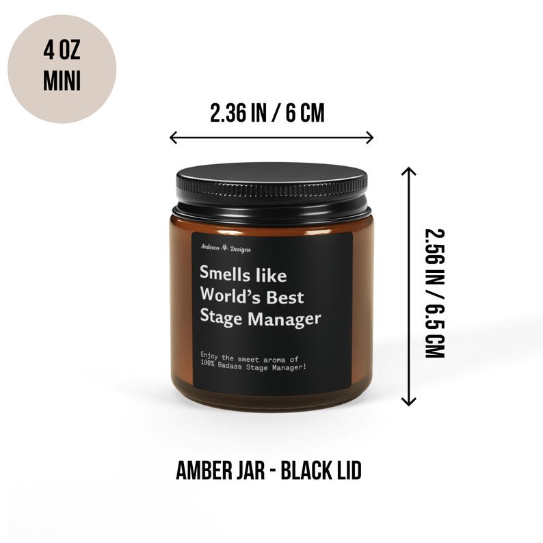 May include: A 4 ounce amber glass candle jar with a black lid. The candle is labelled "Smells like World's Best Stage Manager" and has the text "Enjoy the sweet aroma of 100% Badass Stage Manager!" The jar is 6 cm wide and 6.5 cm tall.