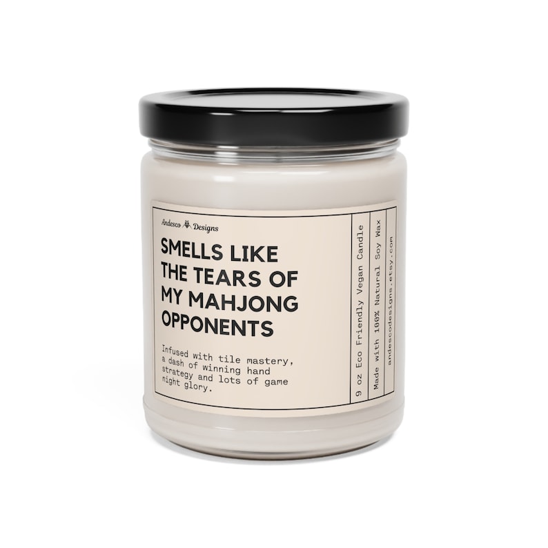 May include: A 9 ounce soy wax candle in a clear glass jar with a black lid. The candle is labeled "Smells Like The Tears Of My Mahjong Opponents". The label also says "Infused with tile mastery, a dash of winning hand strategy and lots of game night glory." and "Made with 100% Natural Soy Wax 9 oz Eco Friendly Vegan Candle andescodesigns.etsy.com"